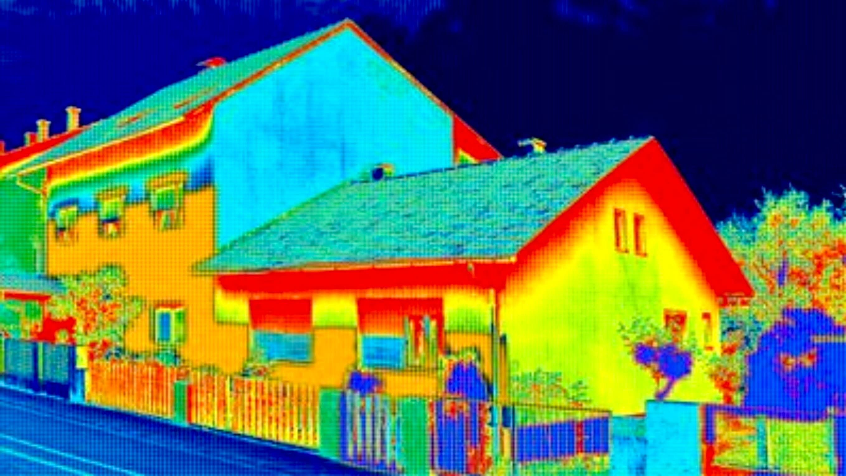 Thermographic image of a house showing heat escaping through walls and windows in bright colors.